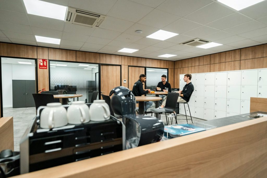 Drei Personen unterhalten sich in einem modernen Büroraum.